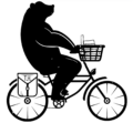 A bear riding a bicycle with a basked on the front full of books